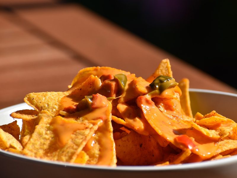 A bowl of nachos with melted cheese and jalapenos