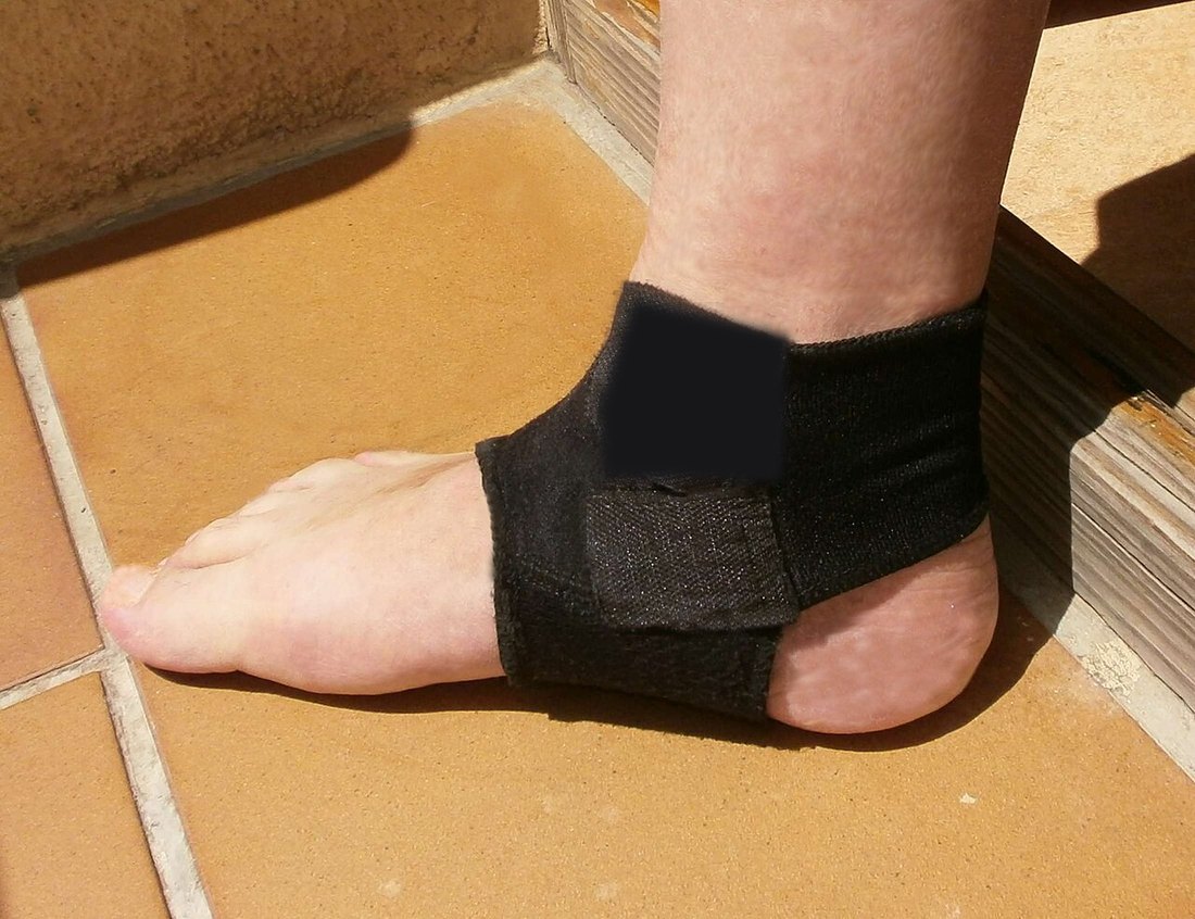 Black strap-style ankle support worn around the ankle