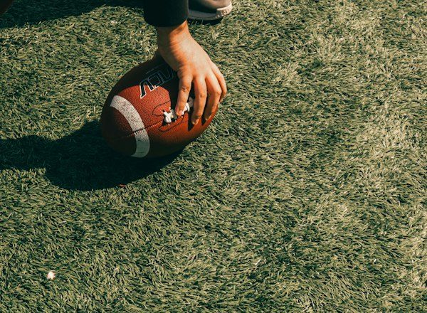 Holding a football on a grassy field