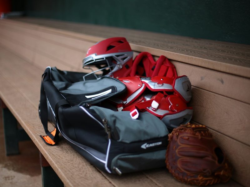 A large equipment bag and helmet on a dugout bench