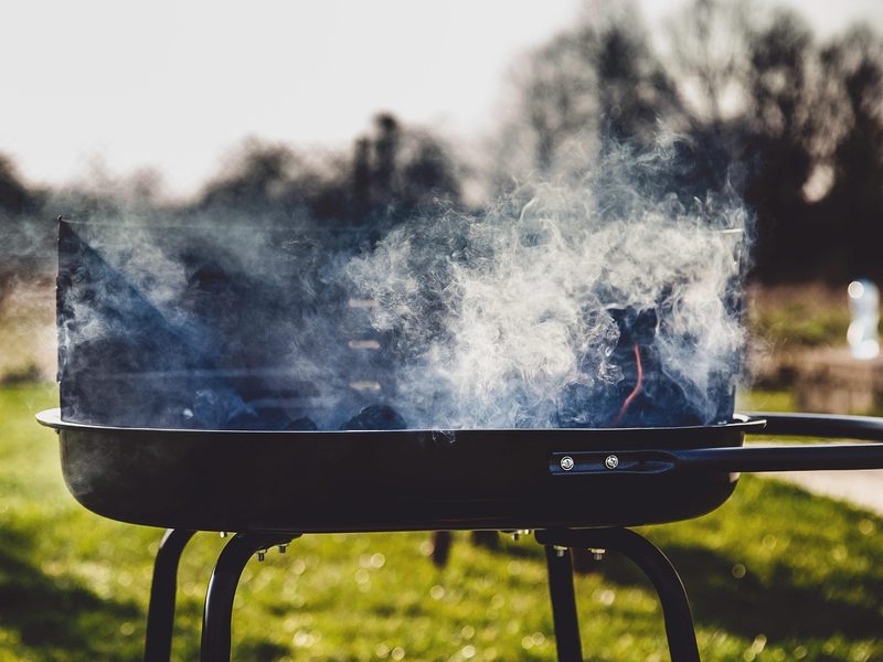 A small outdoor grill smoking on a grass lot